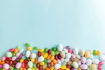 Happy Easter concept. Preparation for holiday. Easter candy chocolate eggs and jellybean sweets isolated on trendy pastel blue background. Simple minimalism flat lay top view copy space.