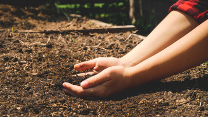 Female farmer holding fertilized soil in hands