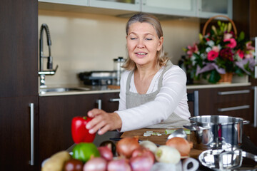 Obraz na płótnie Canvas Senior woman in kitchen preparing food.