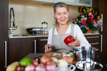 Senior woman in kitchen preparing food.