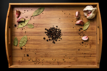 Allspice on a wooden background. Garlic and bay leaf. View from above. Seasoning flavoring for meat and food..