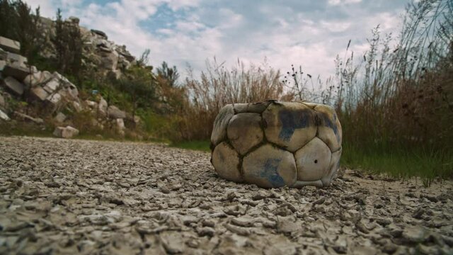 Deflated old football lying on the ground. Aged and useless soccer ball thrown out