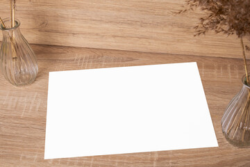 A blank sheet of paper. The photo. In the interior. For text or image. Nearby are dried flowers in vases..