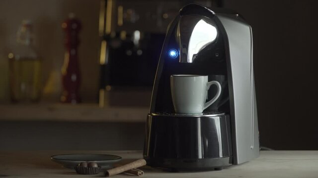 Automatic coffee machine or coffeemaker pouring espresso coffee at home in a cup.