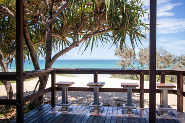 wooden bar and seats under the shade of a palm tree with a view out to the ocean in Sunshine Coast, Australia
