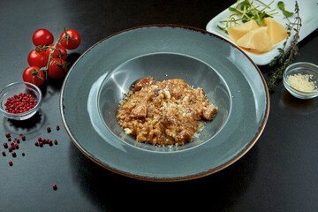 Classic risotto with parmesan and sauce, porcini mushrooms in a plate on a dark background. Italian Cuisine