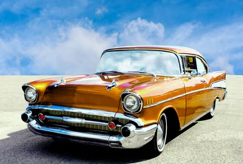 Fotobehang Zijaanzicht van een klassieke Amerikaanse auto uit de jaren vijftig. De auto is in uitstekende staat gezien de glanzende lak. © mikevanschoonderwalt