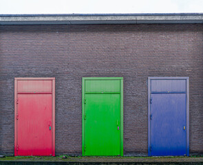 Brick wall with three colored doors