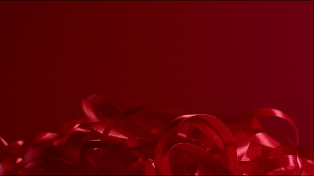 Background for st. valentines day. Romantic atmosphere seamless background. A bunch of dark red silk ribbon falling down on a dark red matte background. Full HD still high quality video
