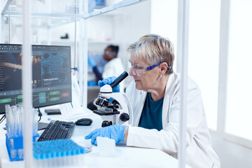 Senior scientist doing medical analysis and engineering using microscope. Elderly researcher...