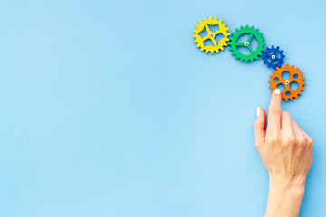 Teamwork concept. Hand connecting gears into puzzle - symbol of working mechanism