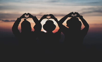 Fototapeta premium The silhouette of the three girls in the evening heart shaped shadow low light.
