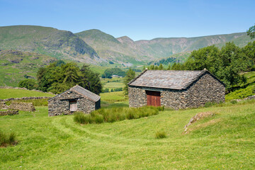 Fototapeta na wymiar Two stone barns in the valley near Kentmere with the summits of