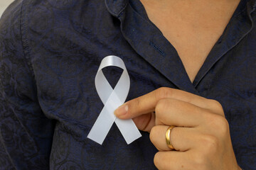 woman putting white ribbon on her shirt. represents a mental health prevention program. White...