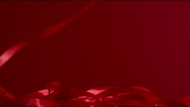 Dark red shiny silky ribbon falling down in a circular movement on a gradient granate matte backdrop. Seamless background. New year and Christmas festive mood. FHD still high quality video footage.