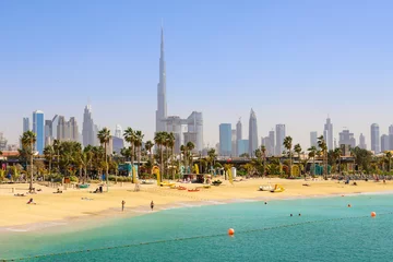 Foto op Plexiglas Dubai strand La Mer, mensen rusten, in de verte de wolkenkrabbers van de stad. Verenigde Arabische Emiraten Dubai maart 2019 © SERGEY