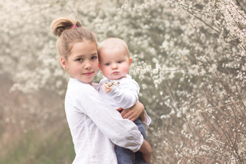 Fototapeta premium Sister with her young baby brother outdoor. Family spring concept