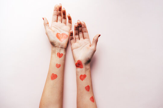 Body-art painted red hearts on the skin of female hands. Celebrating Valentine's Day.