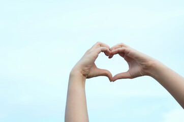 heart-shaped hands on a blue sky background