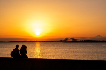 夕焼けの東京ゲートブリッジを眺めるカップルのシルエット