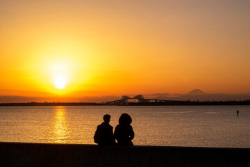 夕焼けの東京ゲートブリッジを眺めるカップルのシルエット