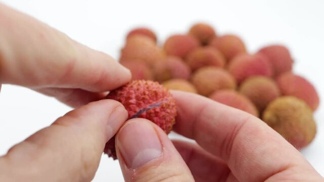 Showing a lychee and its pulp to the camera