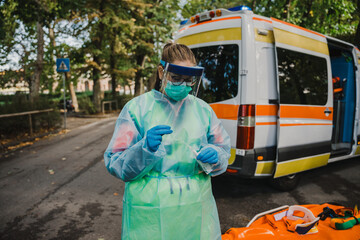 Young doctor with protective suit and face mask prepares swab for a patient on the street next to the ambulance - Millennial paramedic at work during the global Covid-19 pandemic, Coronavirus