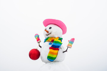 Funny snowman with Christmas toy new year ball. Snow man in pink stylih hat and scarf. Merry Christmas and Happy new year.