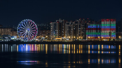 Panorama of the Kazan embankment, a Ferris wheel in the night illumination near the Kazan Kremlin on the bank of the Kazanka River, Kazan, Russia