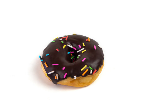 Chocolate flavoured donut with sprinkles on white background. One black doughnut isolated picture. Homemade bakery concept.
