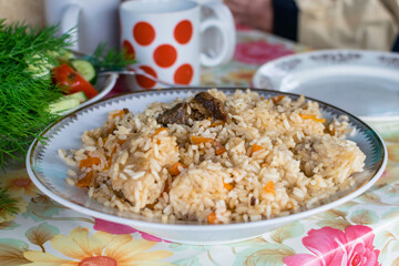 A plate of pilaf on a table with carrots and meat