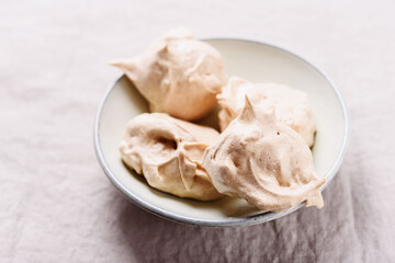 Homemade sweet meringue cookies on greige linen tablecloth. Delicious and light dessert. Selective focus