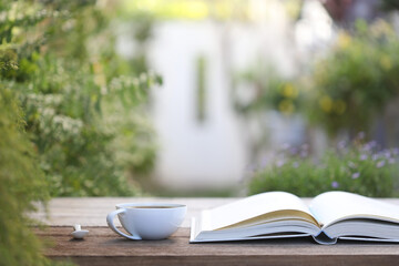 white coffee cup and open notebook on wooden table outside