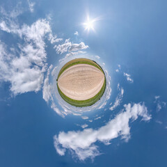 green tiny planet in blue sky with sun and beautiful clouds. Transformation of spherical panorama 360 degrees. Spherical abstract aerial view. Curvature of space.