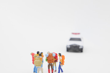 話し合う旅行者を規制しようとするパトカーのミニチュア   © komta