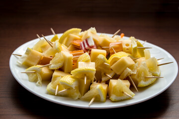Canapes with cheese, lemon and marmalade on a white plate. Wooden table background. Fresh and healthy food. Diet