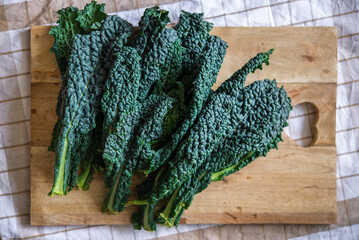 Black cabbage of Tuscany, also called tuscan kale or lacinato, fresh and raw on a wooden kitchen board, top view