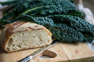 Peasant food: homemade bread and black tuscan cabbage on wooden cutting board, selective focus on bread.