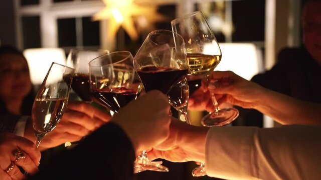 Low light. narrow depth of field. hands with glasses of wine and champagne are clink. Family holiday in a country house. alcoholic beverages. Hospitality.