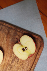 half of an apple on wooden plate on a napkin flat lay