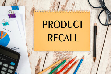 Notebook with text PRODUCT RECALL near office supplies.