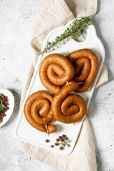 Spiral smoked sausages on a serving Board on a light gray table. Spiral sausages. Homemade meat fried sausages