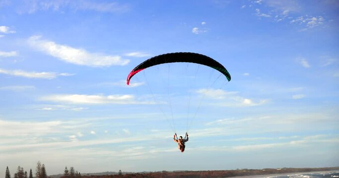 Hanglider flying over ocean and cliffside in Cabarita Beach, Northern NSW at golden hour with lovely golden light