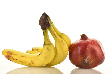 Fresh fruits - three bananas and one pomegranate, close-up, isolated on white.