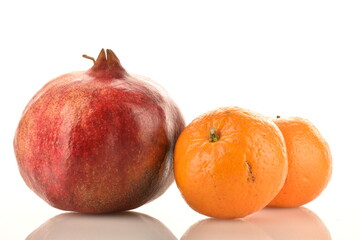 Fresh fruits - two tangerines and one pomegranate, close-up, isolated on white.