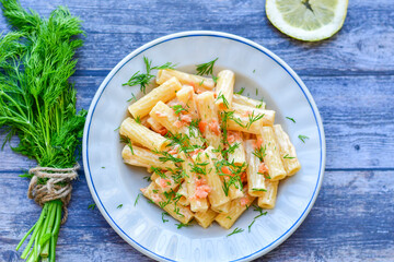  Italian home made  macaroni pasta with smoked salmon , creamy sauce and fresh dill on wooden background