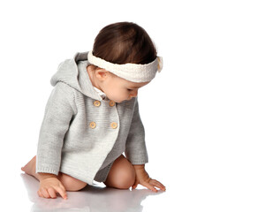 Interested curious baby in knitted wear and headband isolated portrait. Infant child crawling on white studio floor background. Innocence, curiosity, babyhood concept. Children style and fashion
