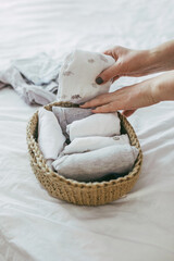 Woman folding clothes in jute basket in the konmari system. Concept of organizing minimalism clothes
