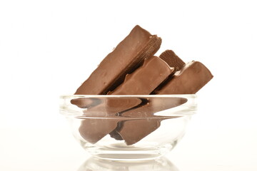 Several sweet chocolate bars in a glass bowl, close-up, isolated on white.