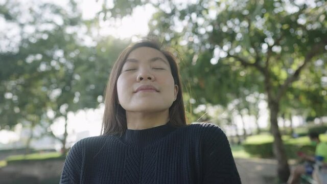 Asian woman aking deep breath to exhaling fresh air in the park
